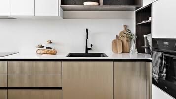 A modern kitchen with a herringbone wood floor, a black faucet, and a built-in oven.