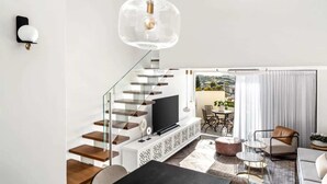 A modern living room with a staircase, a TV, and a dining area. - Private Parking Beachfront Duplex | Shelter (Herzliya)