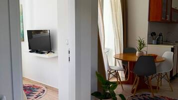 Un espacio de estar moderno con comedor, televisor en la pared y área de cocina con armarios.