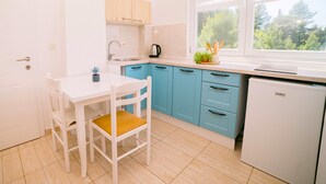 Una cocina moderna con armarios blancos, un lavamanos, una cafetera y una ventana con vistas a árboles.