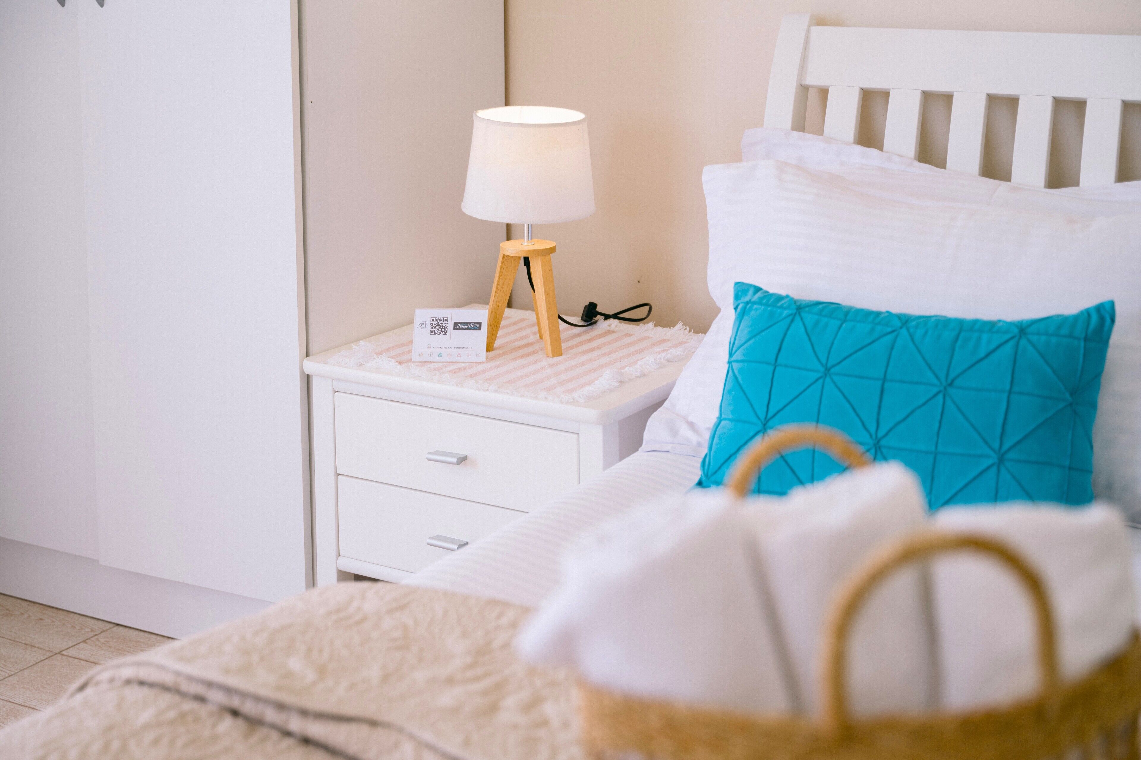 A neatly made bed with a white headboard, a teal pillow, and a white blanket.