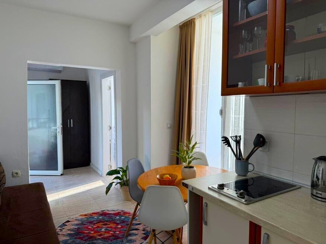Una cocina moderna con comedor, una puerta corrediza que da a un balcón y una pequeña mesa con sillas.