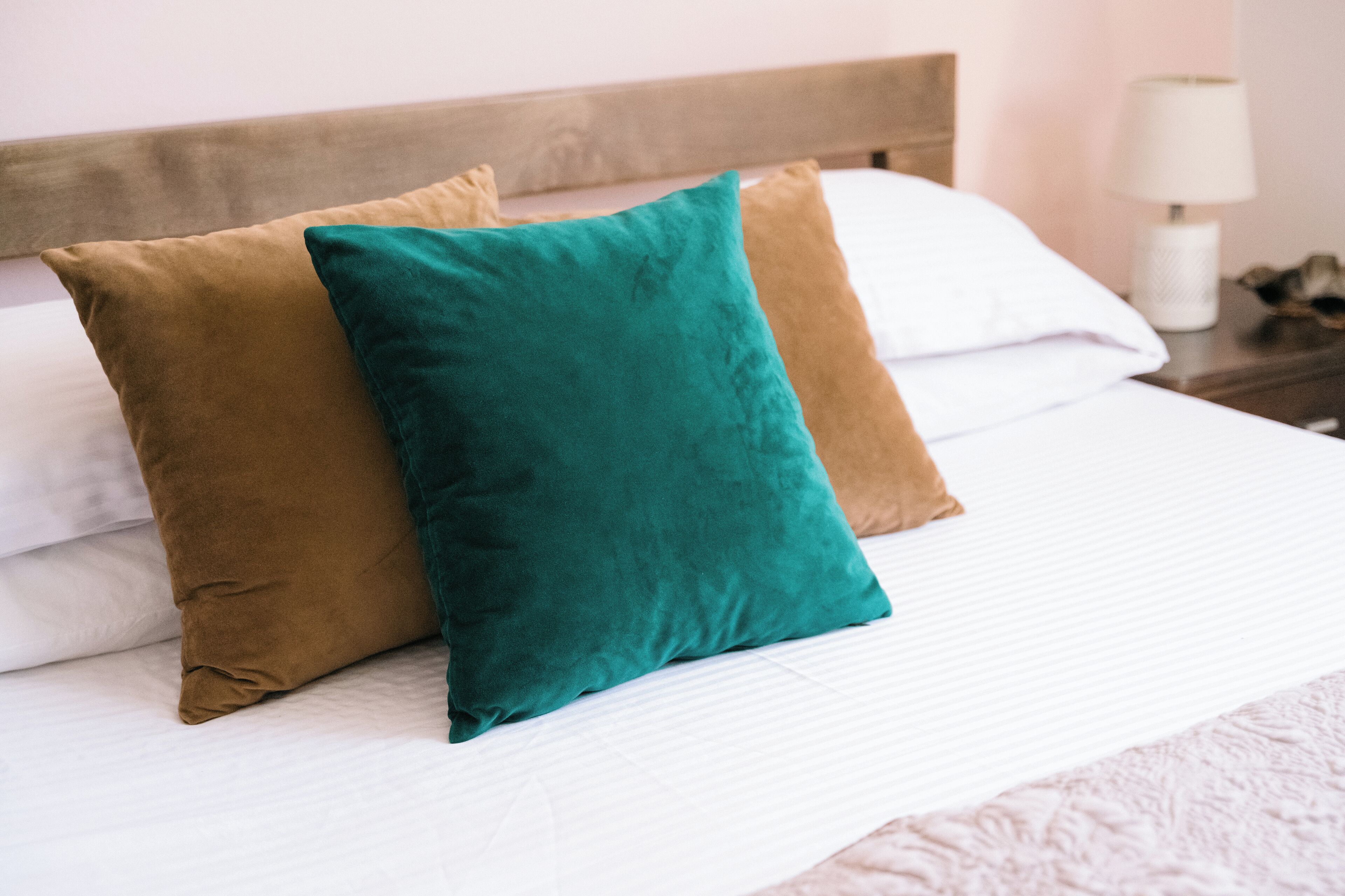 A bed with two pillows, a wooden headboard, and a bedside table with a lamp.