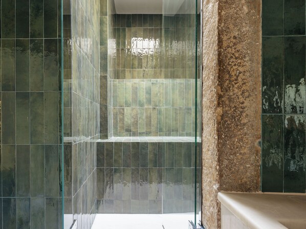 A bathroom with a glass shower enclosure, tiled walls, and a stone accent wall. - Dare Lisbon River (Lisbon)