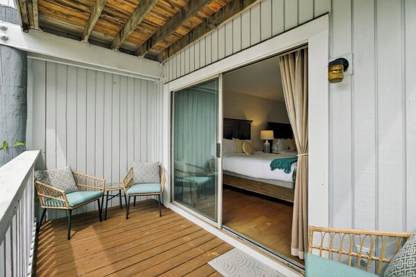 A balcony with wicker chairs and a wooden floor.