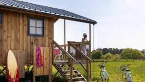 Eine Holzhütte mit Veranda, einem Surfbrett und Fahrrädern.
