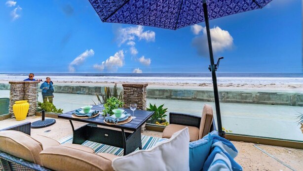A beachside patio with a table set for two, overlooking the ocean.