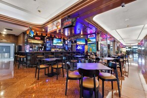 Un restaurante con zona de bar, varias televisiones y diferentes opciones de asientos.