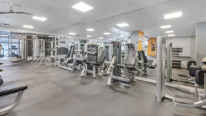 Une salle de sport équipée de divers appareils d’exercice, dotée d’un murmiroir et présentant un design moderne et épuré.