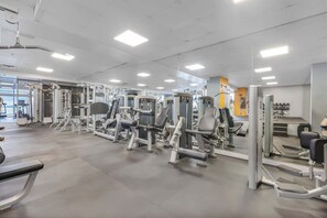 A gym with various exercise machines, a mirrored wall, and a clean, modern design.