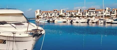 A marina with boats docked and a row of buildings in the background.