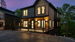 A modern two-story house with a covered porch, large windows, and a well-lit exterior. - Luxe stay, Sleeps 12・Indoor Pool・Hot Tub・Games (Sevierville)