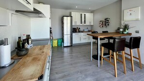 A modern kitchen with white cabinets, a stainless steel refrigerator, and a wooden dining table with black chairs.