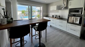 A modern kitchen with a dining area, large windows, and a view of a pool.