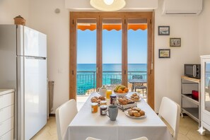 Une cuisine avec vue sur la mer, une table mise pour le petit-déjeuner et un réfrigérateur.
