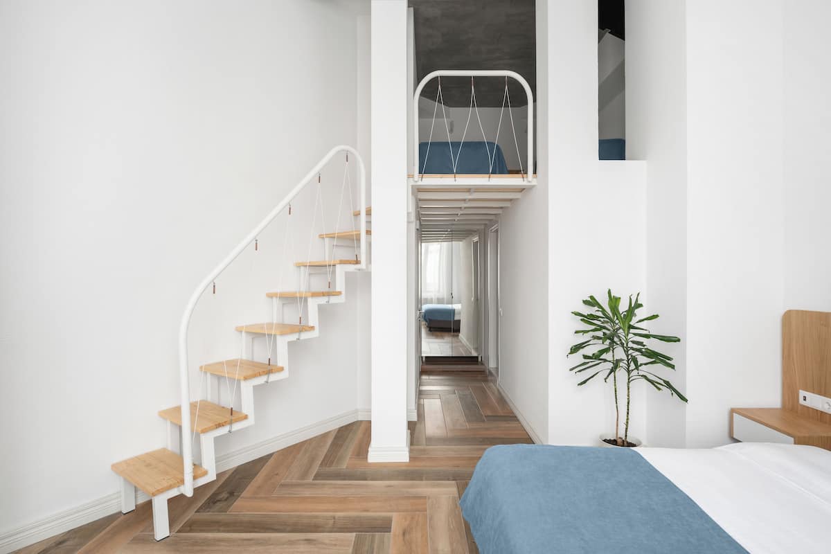 A modern interior with a wooden staircase, a bunk bed, and a potted plant.