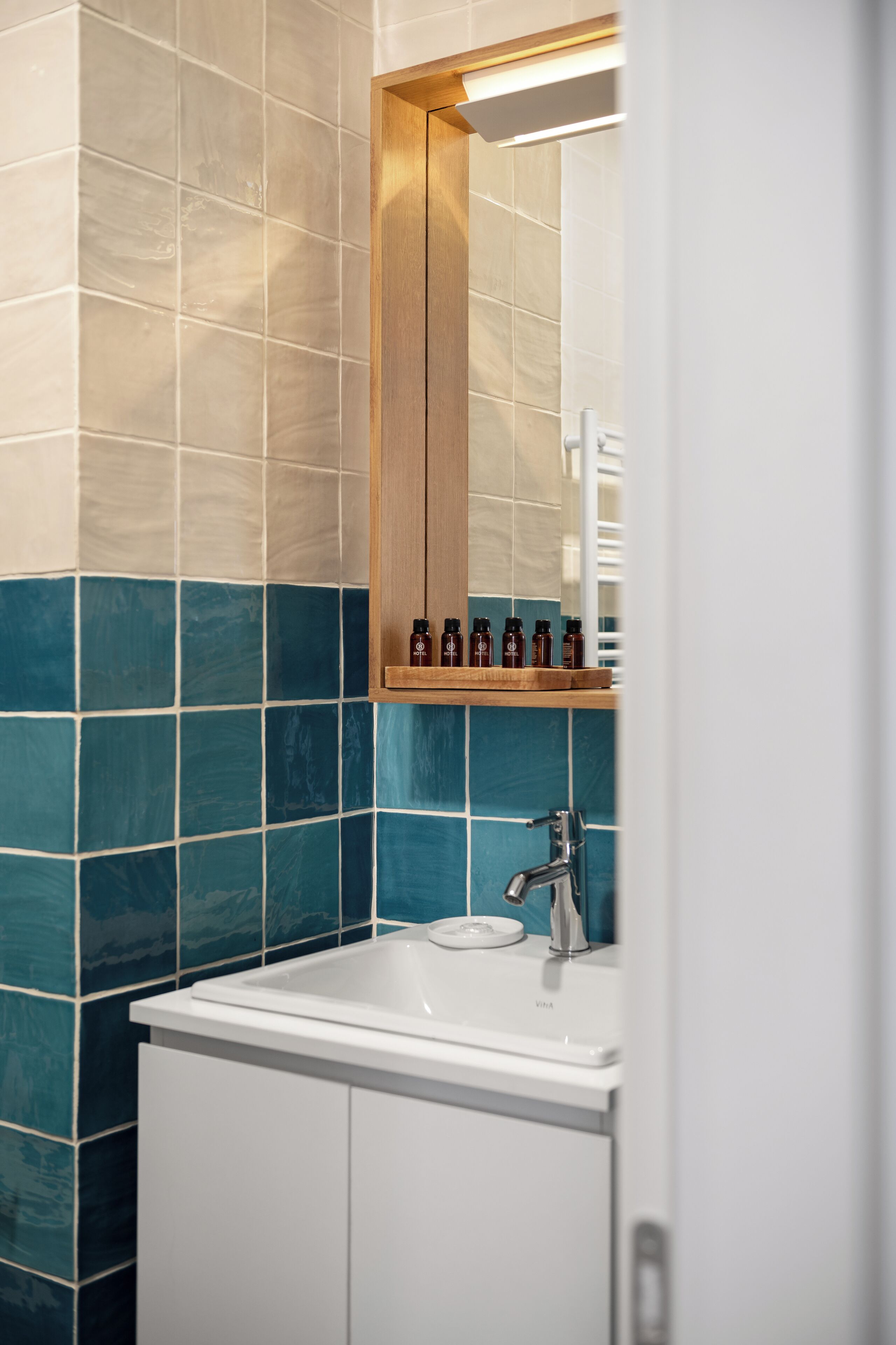 A bathroom with a white sink, a mirror, and a shelf with bottles.