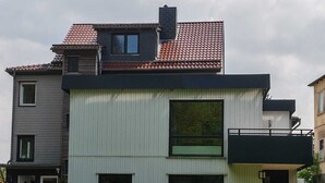Ein modernes, zweistöckiges Haus mit Flachdach und kleinem Balkon.