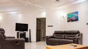 Una sala de estar moderna con un televisor de pantalla plana, dos sofás de cuero, una mesa de centro de madera y un cuadro en la pared.