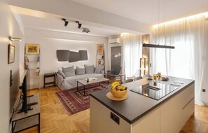 A modern living room with a sofa, coffee table, and a dining area with a fruit bowl and a small island. - Well-designed apartment by the Acropolis (Athens)