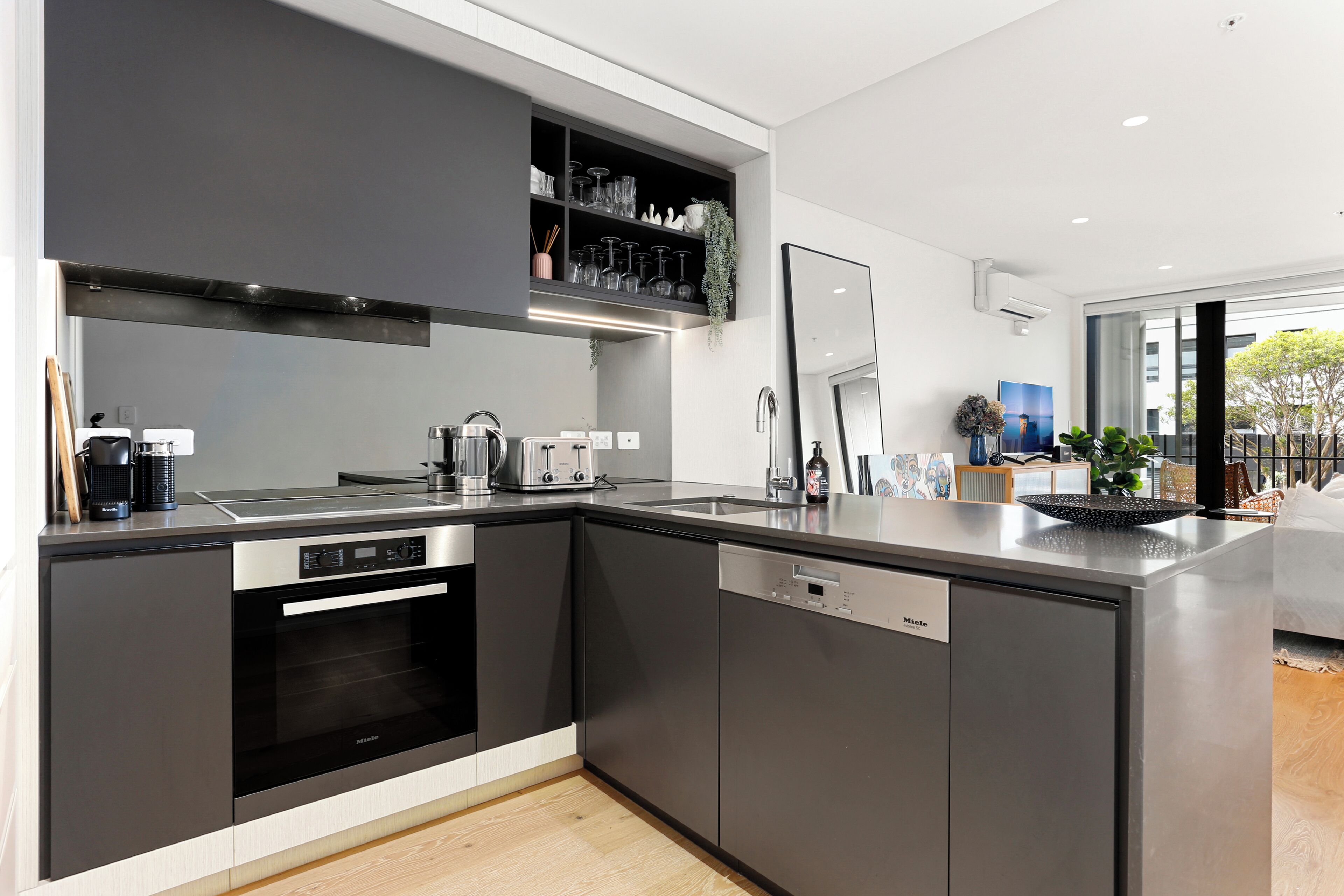 A modern kitchen with built-in appliances, a dishwasher, and a coffee machine.