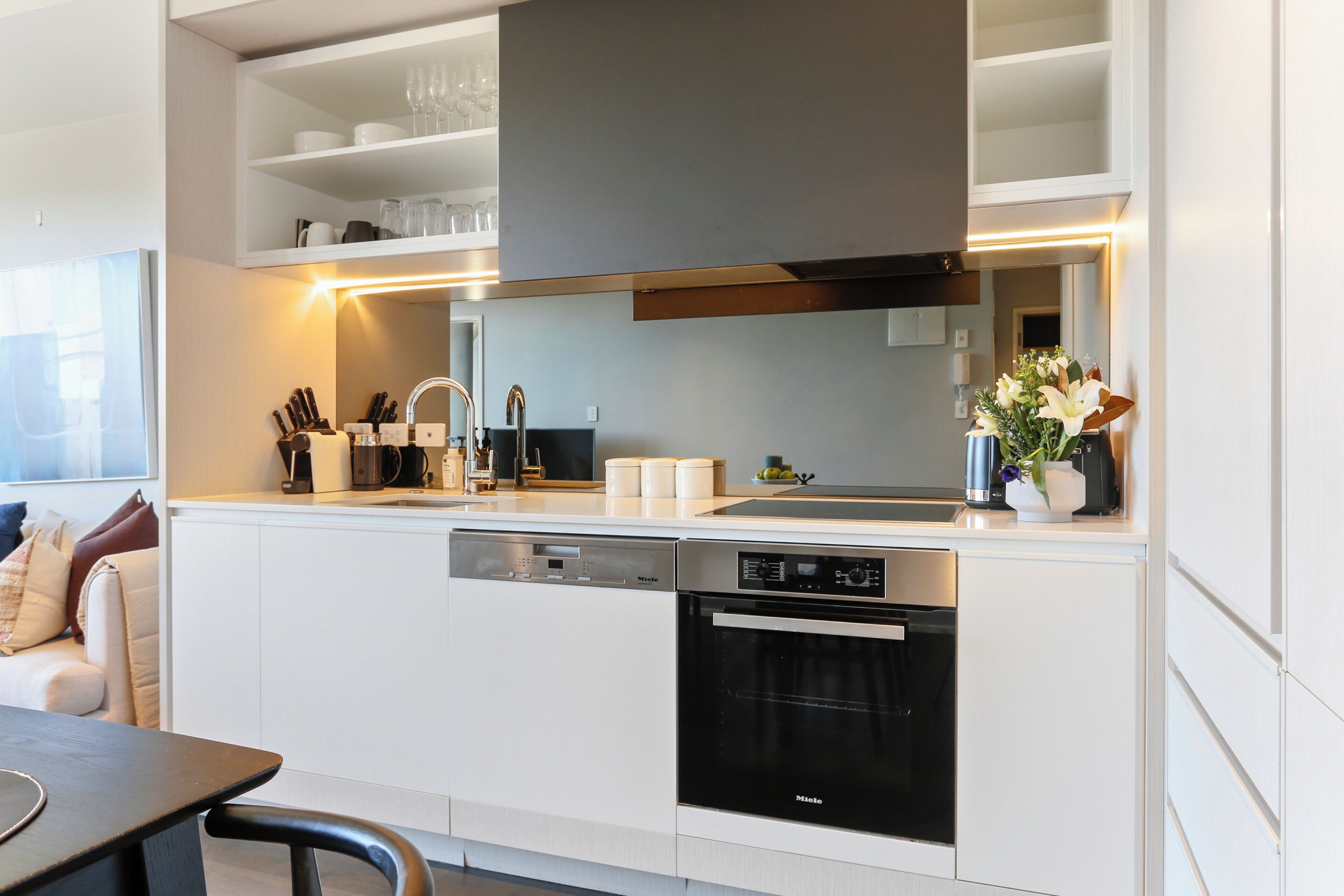 A modern kitchen with built-in appliances, a dining area with a table and chairs, and a window with a view.