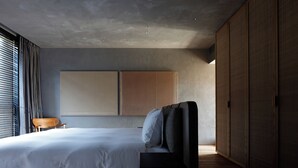 Une chambre à coucher moderne avec un grand lit, une chaise en bois et une armoire.