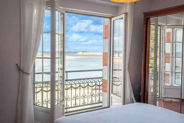 Une chambre avec une grande fenêtre, un lit et une vue sur la mer.