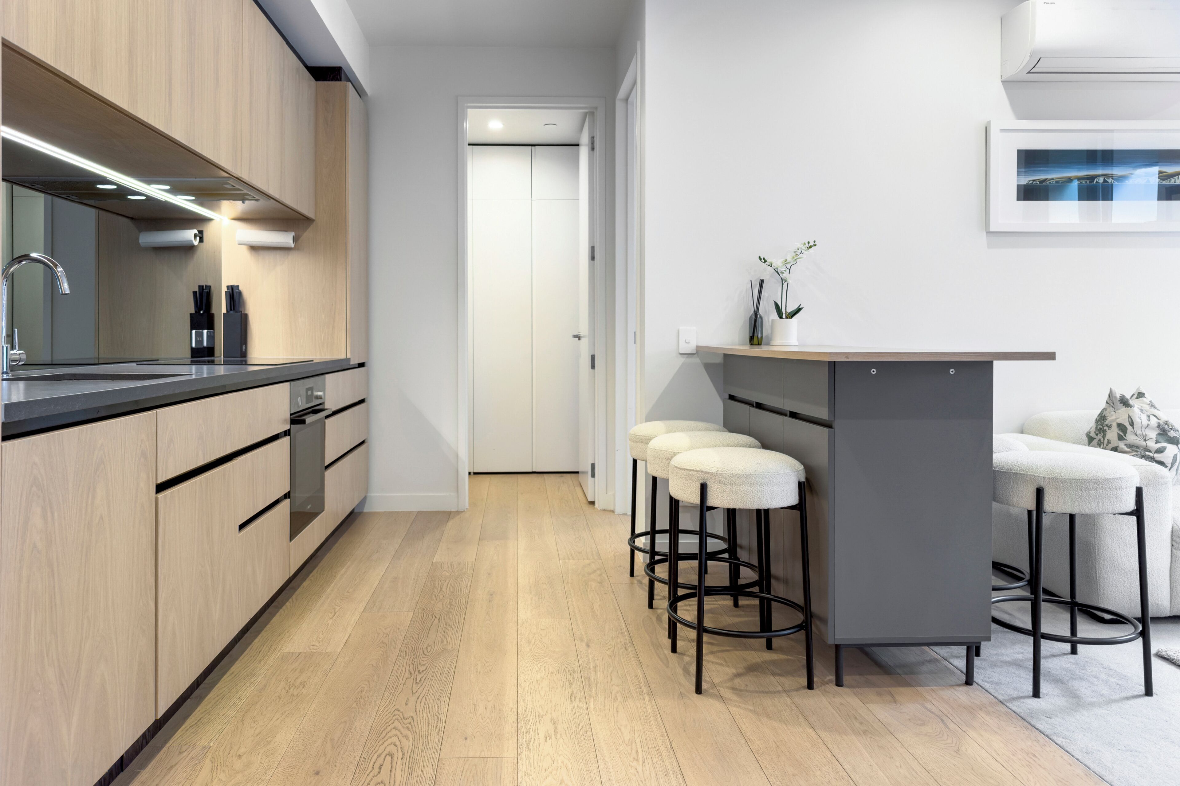 Eine moderne Küche mit Holzschränken, einer Edelstahlspüle und einer Bar mit Sitzgelegenheiten.