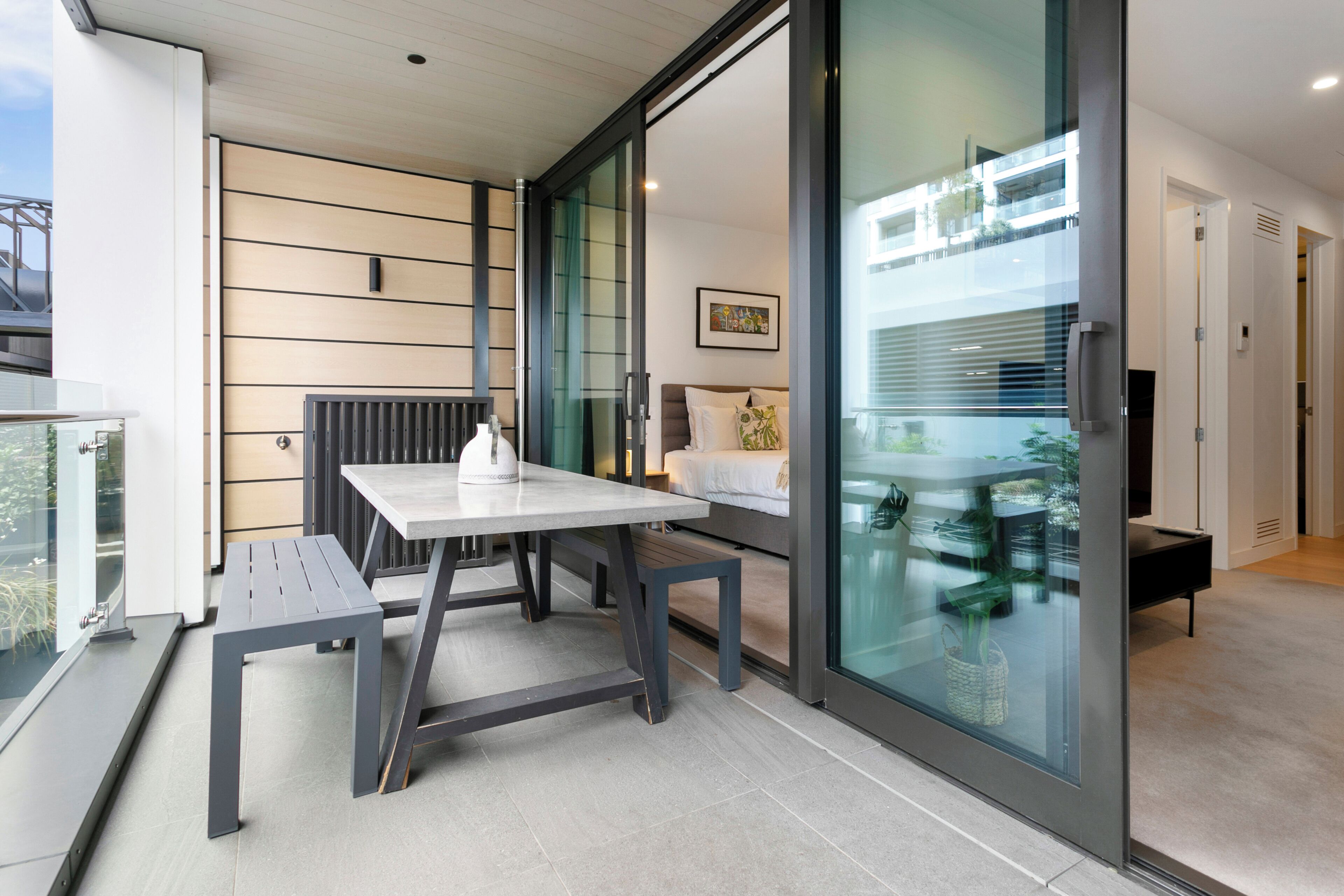 A modern room with a glass partition, a white table, and a bench.
