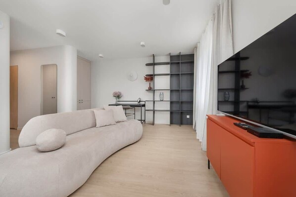 Relax in this stylish living room with a curved sofa, flat-screen TV, and bookshelf.