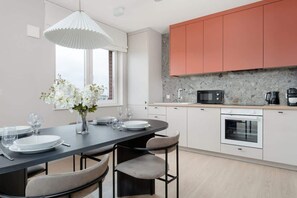 Una cocina moderna con armarios blancos, encimera negra y comedor con mesa y sillas redondas.