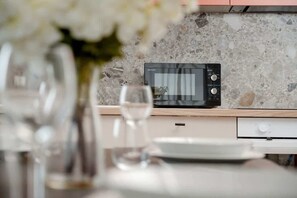 Enjoy a meal in the kitchen, which features a microwave oven, granite backsplash, and wooden cabinets.