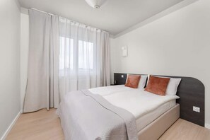 Cozy retreat with a single bed, light duvet, and sheer curtains.