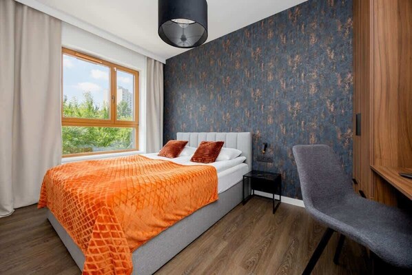 A bedroom with a bed, a chair, a nightstand, a window, and a wall with a textured pattern. - Modern Apartment | Parking | Close to Metro (Warszawa)