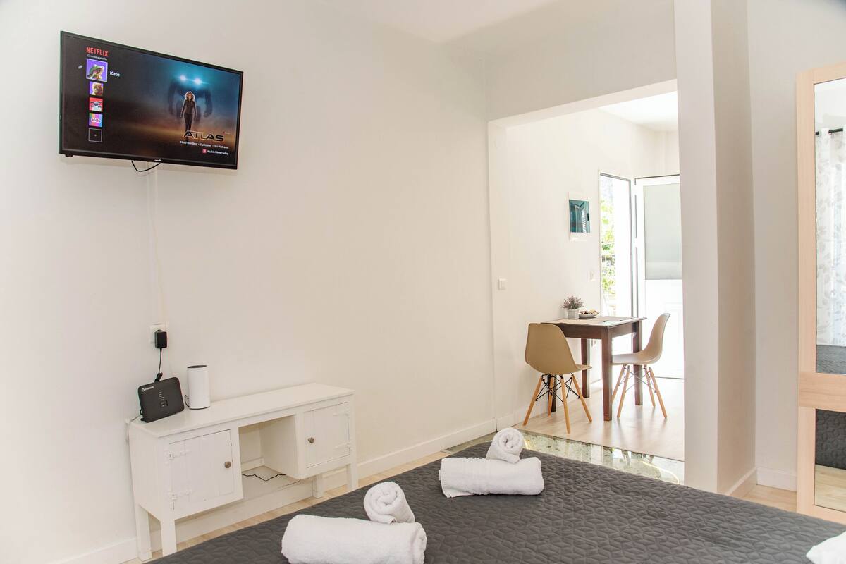 Une chambre d’hôtel avec un lit, un téléviseur fixé au mur, un bureau et une chaise.
