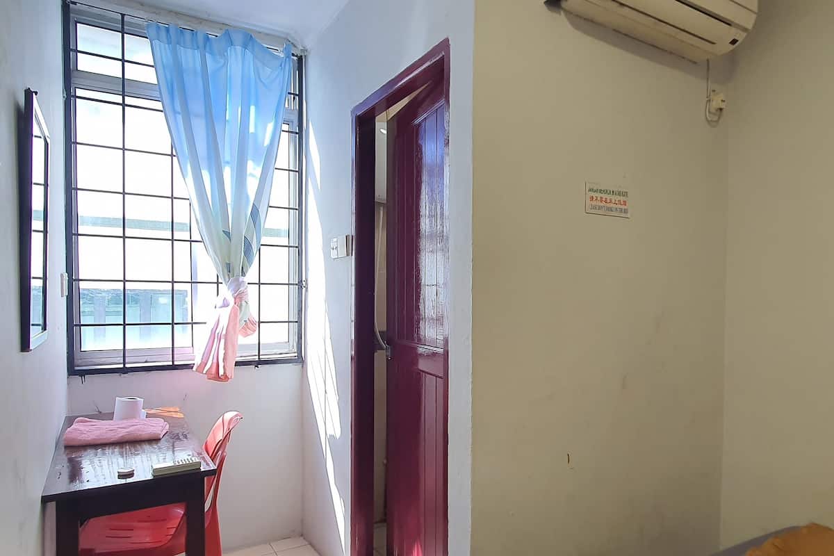 A room with a window, a door, a table with a chair, and a bed.
