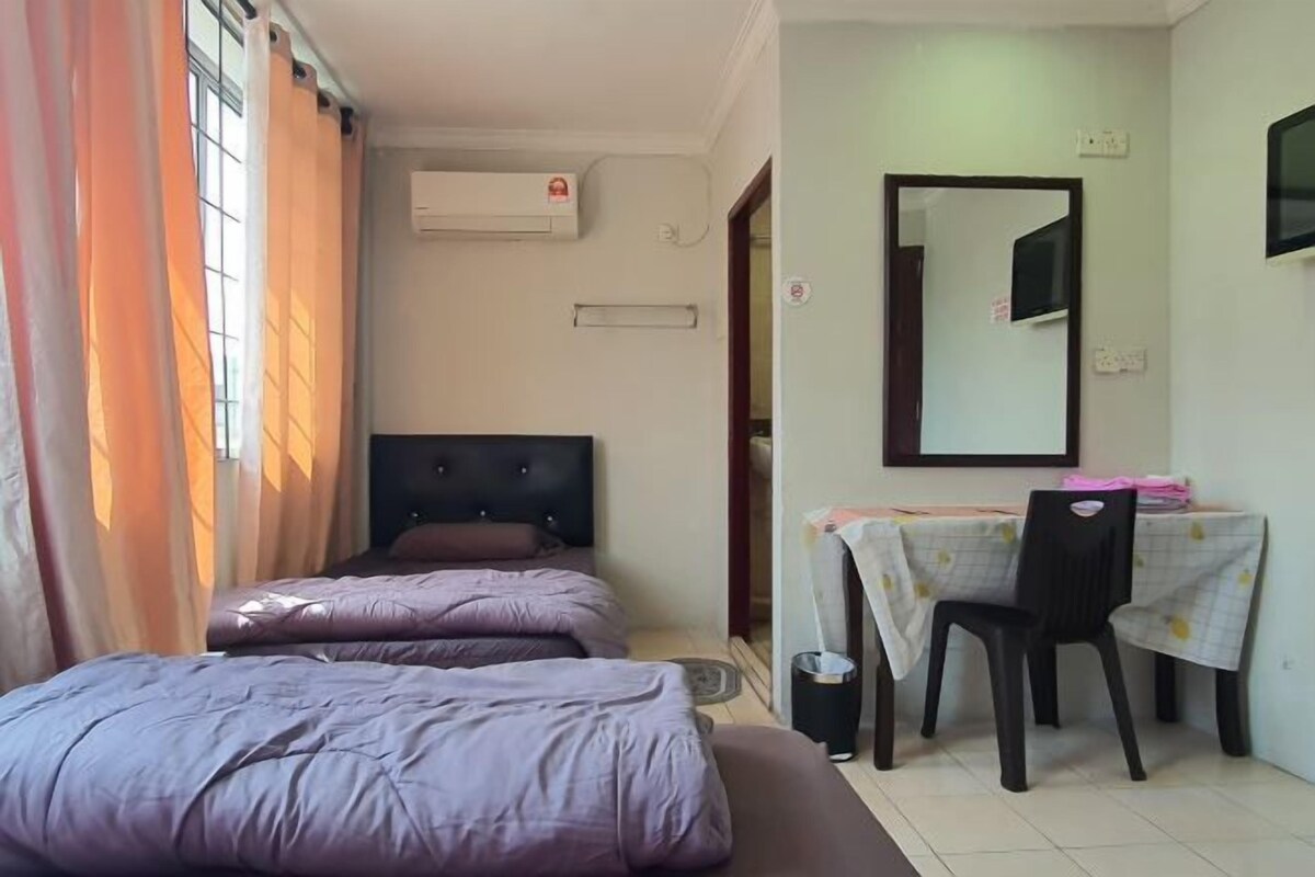 Una habitación con dos camas, un escritorio con silla, un espejo y un aire acondicionado.