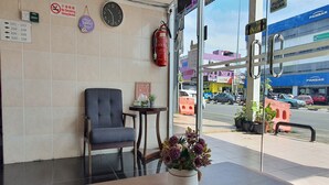 Un vestíbulo de hotel con una silla, una mesa con un florero, un reloj y un letrero de 'No Fumar'.