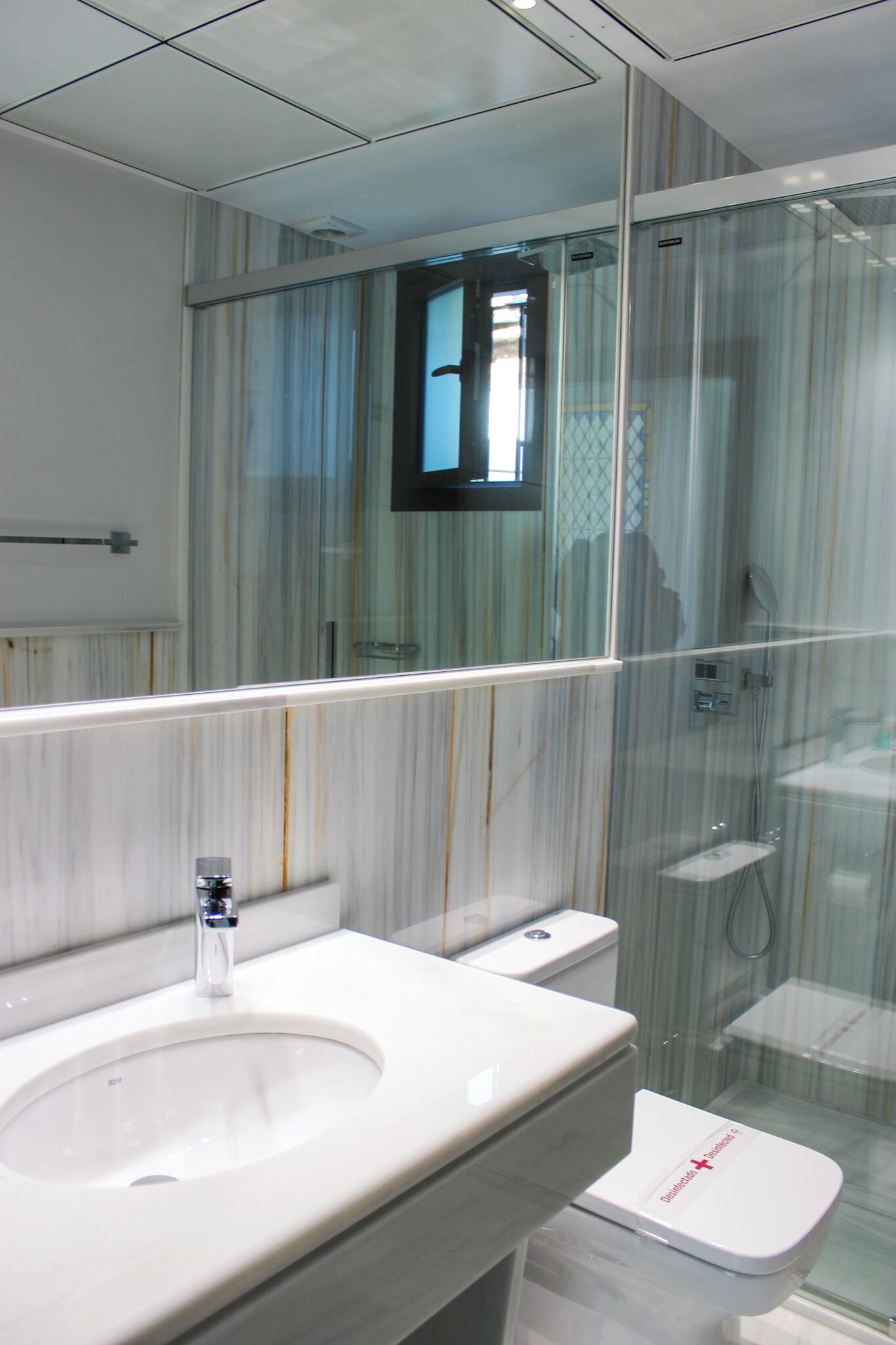 Un baño con un lavamanos blanco, un espejo y una cabina de ducha de vidrio.