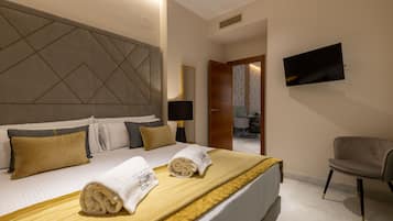 A hotel room with a large bed, a flat-screen TV mounted on the wall, and a chair.