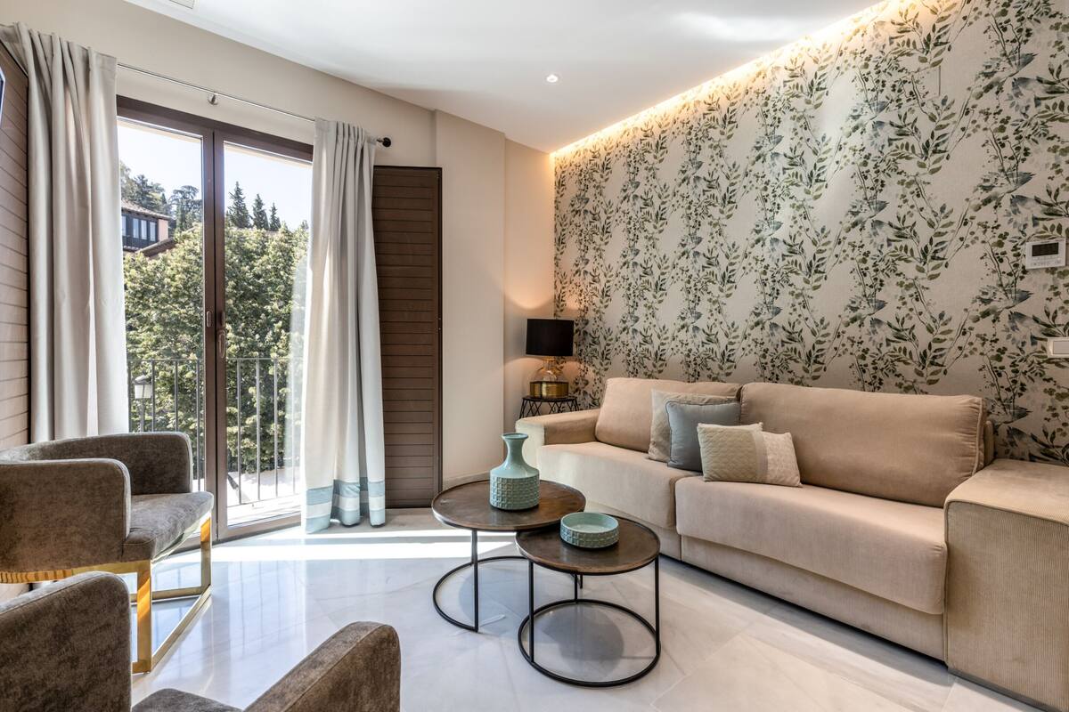 A modern living room with a sofa, two armchairs, a coffee table, and a large window with curtains.