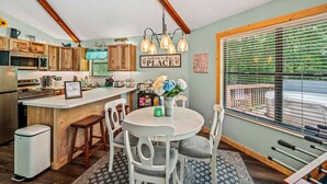 A kitchen with wooden cabinets, a central island, and a dining area with a round table and chairs.