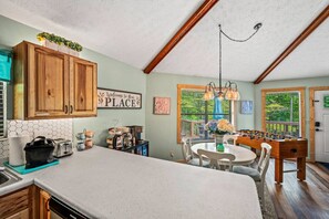 A kitchen with wooden cabinets, a coffee station, and a foosball table.