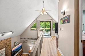 A spacious hallway with a wooden floor, a ceiling fan, and a view to an outdoor deck.