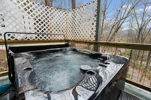 A hot tub on an outdoor deck with a lattice fence in the background.