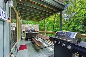 An outdoor deck with a grill, a table, and a bench.