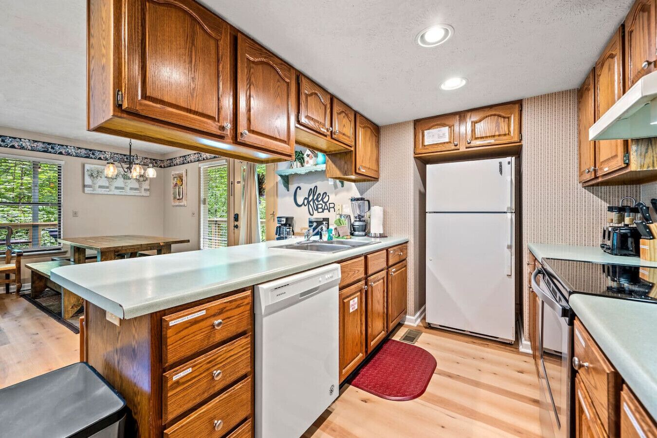 A compact kitchen with wooden cabinets, a built-in dishwasher, and a refrigerator.