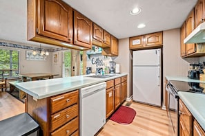 A compact kitchen with wooden cabinets, a built-in dishwasher, and a refrigerator.