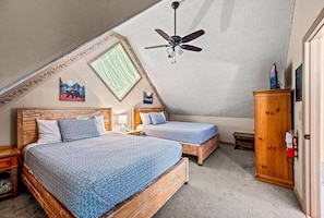 Un dormitorio con dos camas, un ventilador de techo, un armario de madera y un extintor.